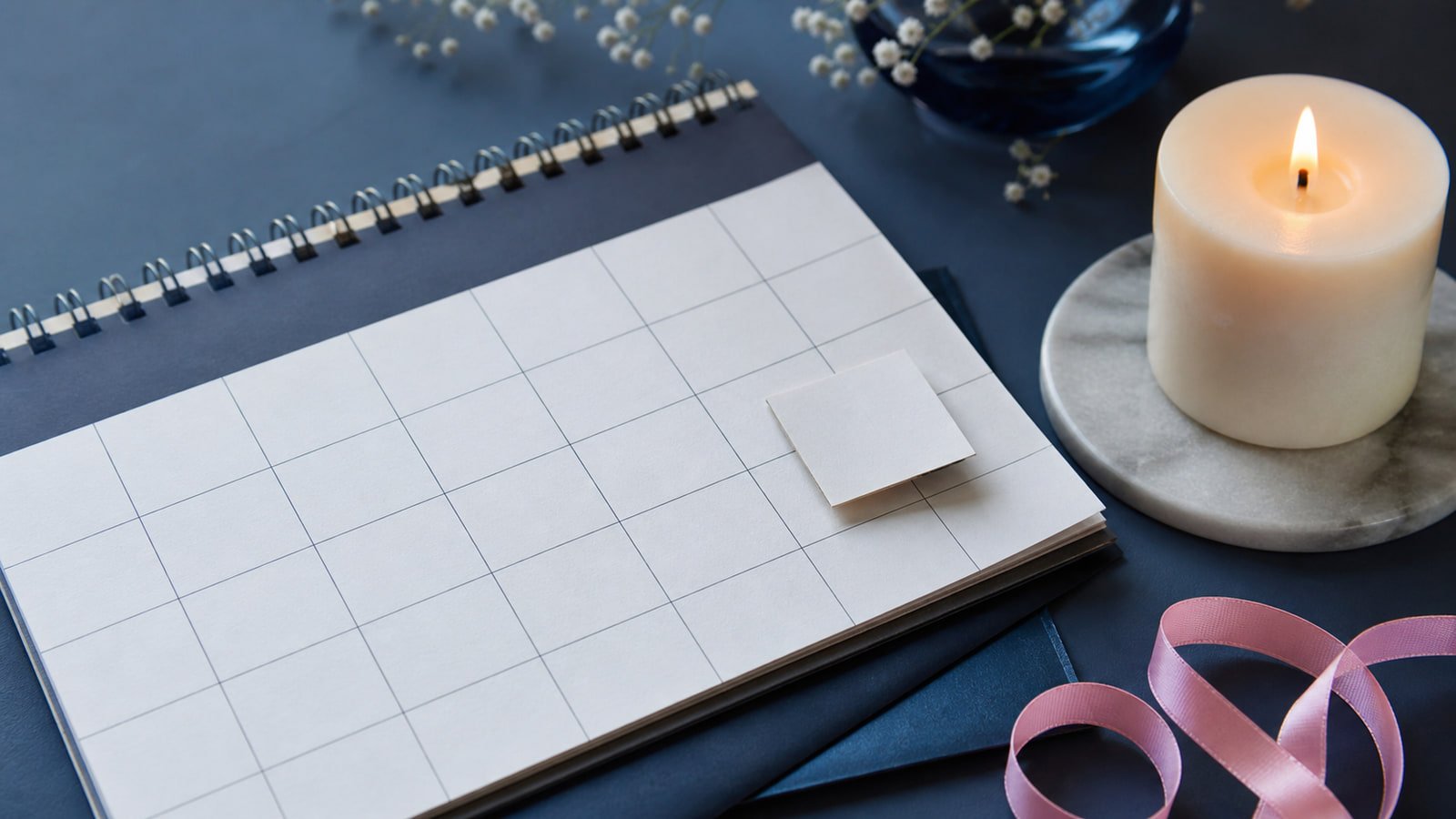 A raised calendar tile, candle, and pink ribbon form a restrained leap-year birthday scene.